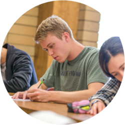 A student sits at a desk working on an assignment for class.